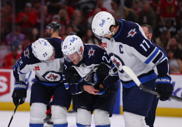 egv250412039_wpg_vs_chi(1) Mason Appleton #22 of the Winnipeg Jets helps Nikolaj Ehlers #27 of the Winnipeg Jets to the bench during the second period against the Chicago Blackhawks on April 12. 2025 at the United Center in Chicago, Illinois.