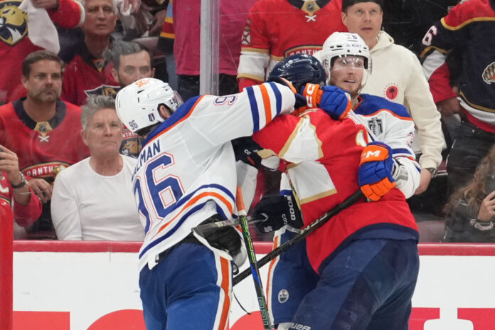 SUNRISE, FL - JUNE 09: while being held by an Edmonton players, Edmonton Oilers defenseman Jake Walman (96) punches Florida Panthers left wing Matthew Tkachuk (19) in the face in the third period during game three of the Stanley Cup Finals between the Edmonton Oilers and the Florida Panthers on June 9, 2025 at Amerant Bank Arena, FL. SUNRISE, FL - JUNE 09: while being held by an Edmonton players, Edmonton Oilers defenseman Jake Walman (96) punches Florida Panthers left wing Matthew Tkachuk (19) in the face in the third period during game three of the Stanley Cup Finals between the Edmonton Oilers and the Florida Panthers on June 9, 2025 at Amerant Bank Arena, FL.