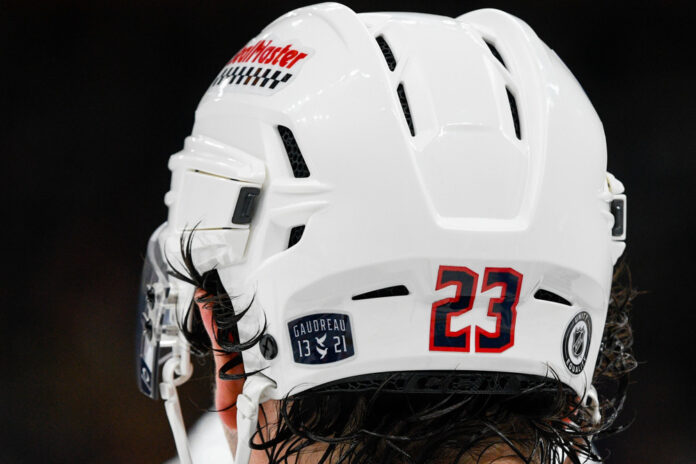 NHL: DEC 28 Blue Jackets at Bruins Gaudreau 13 21 helmet decal honoring Johnny Gaudreau and Matthew Gaudreau on Sean Monahan's Blue Jackets helmet