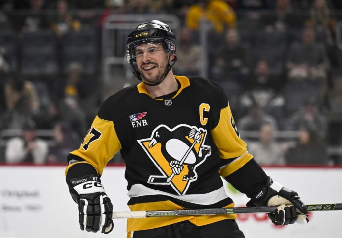 crosby-smile-col-pit-march-2026 Sidney Crosby Pittsburgh Penguins captain smiles after face-off in NHL game between Penguins and Colorado Avalanche at PPG Paints Arena