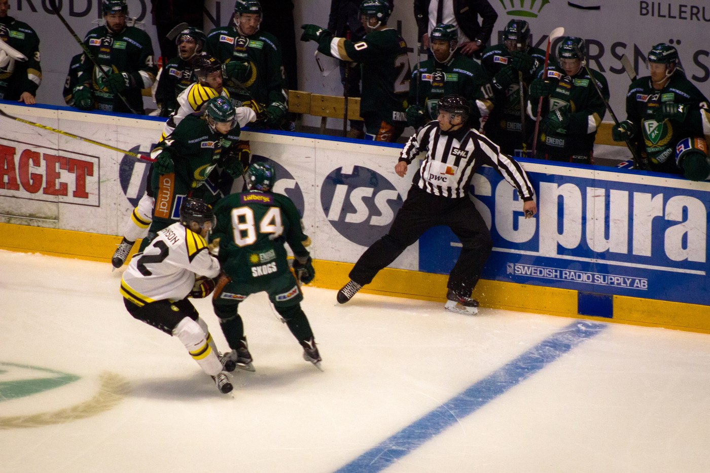 Farjestad BK players in green battle along the boards during an SHL game in Karlstad, Sweden