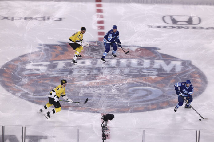 Players skate over the center ice logo at the NHL Stadium Series