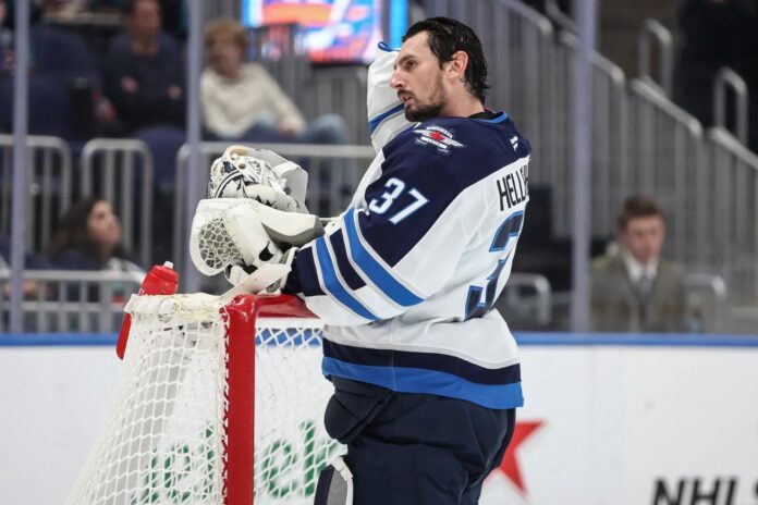 Connor Hellebuyck Jets trade request NHL CBA Winnipeg Jets goaltender Connor Hellebuyck leans on the net during a timeout against the New York Islanders