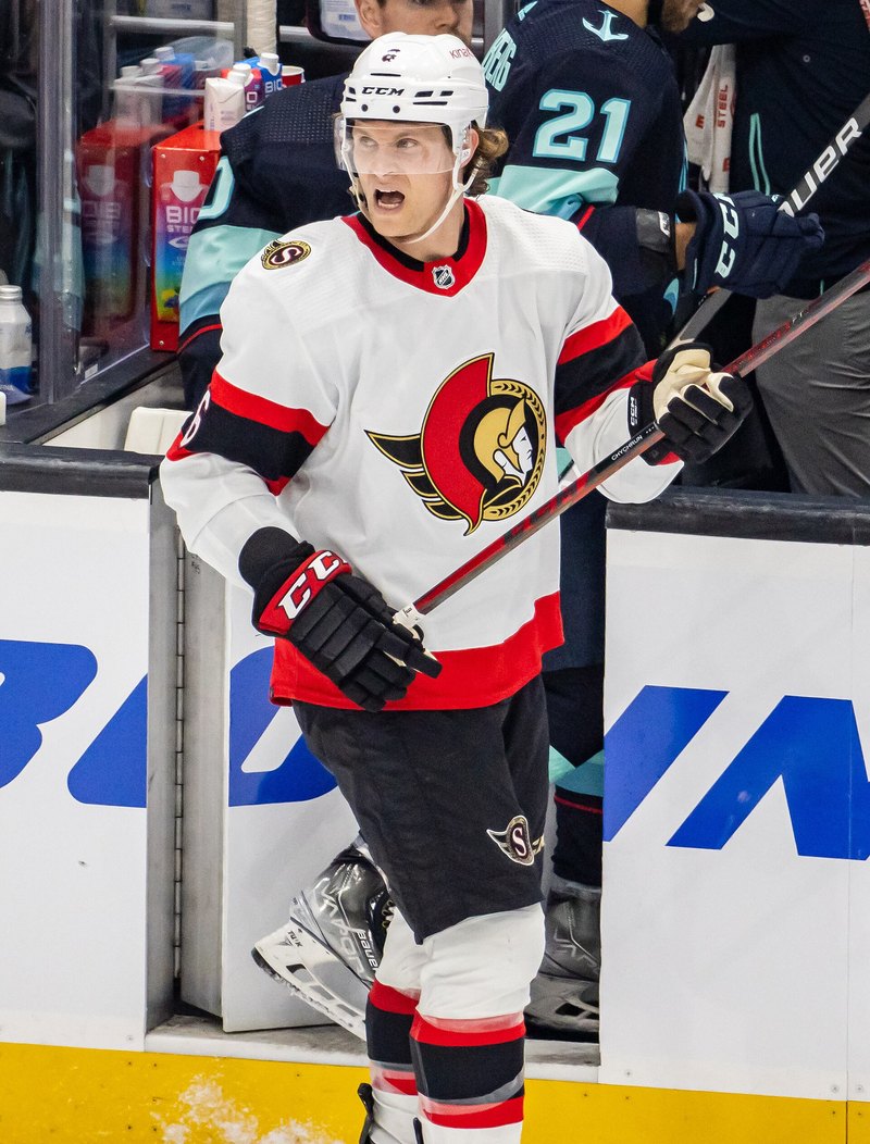 Jakob Chychrun in a white Ottawa Senators jersey near the bench