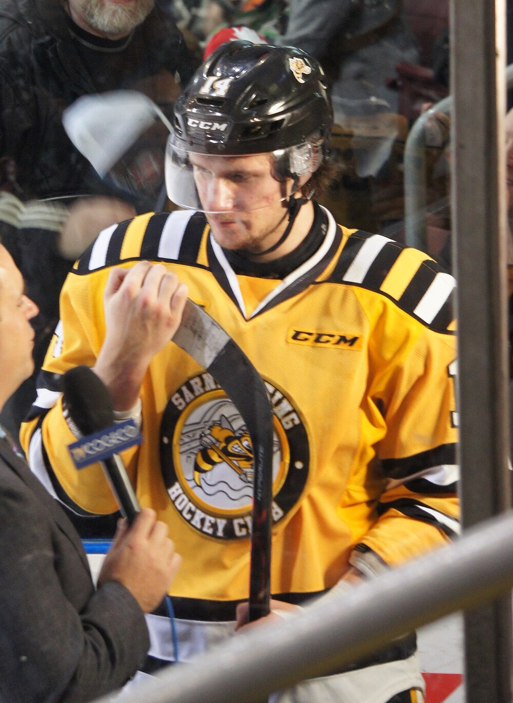 Pavel Zacha in a Sarnia Sting jersey signs a stick beside the boards