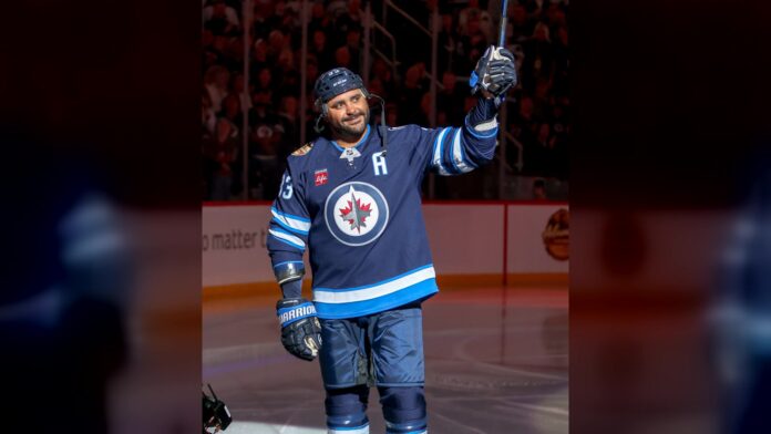 Dustin Byfuglien Jets alumni game Dustin Byfuglien raises his stick to the crowd in a Winnipeg Jets sweater during the Jets alumni game