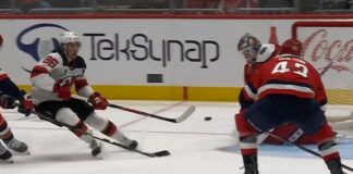 Jack Hughes Devils shoots backhand as Tom Wilson Capitals closes in during Devils-Capitals game