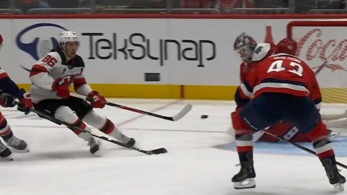 Jack Hughes Tom Wilson Devils Capitals Jack Hughes Devils shoots backhand as Tom Wilson Capitals closes in during Devils-Capitals game