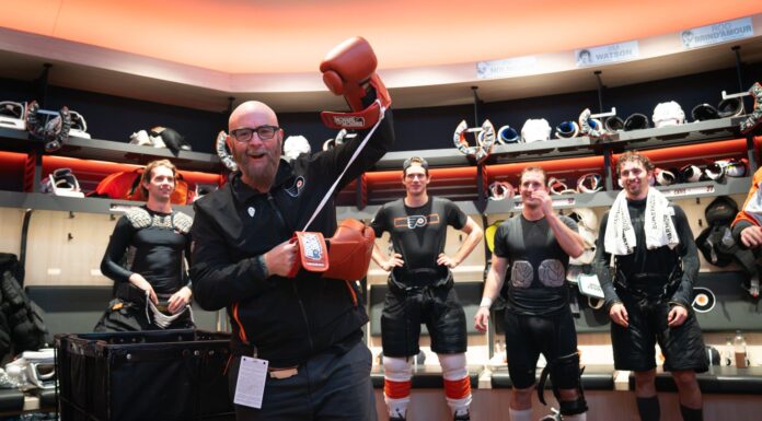 Tocchet Game Puck: Flyers Coach Honors Jason Myrtetus Jason Myrtetus Flyers radio broadcaster holding Rocky gloves in locker room